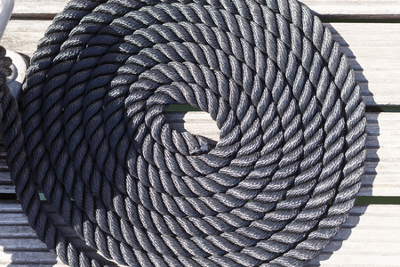 Close-up of a mooring rope on a wooden pier/ Nautical mooring rope