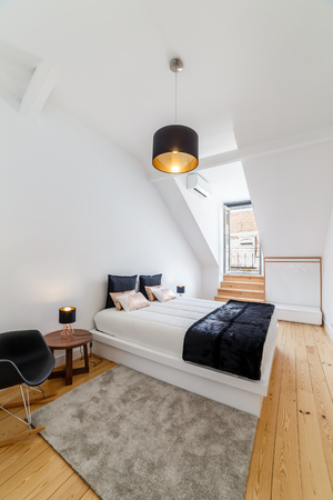 Modern master bedroom in apartment with white walls and light wooden floorの写真素材