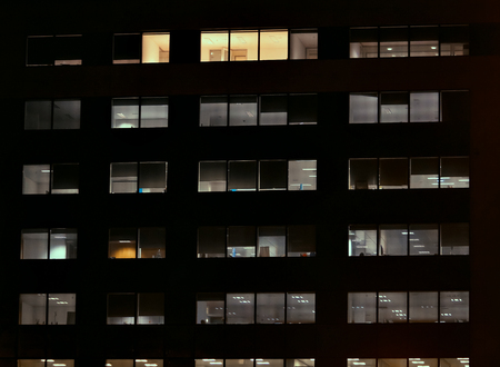 Frontal view of the night facade of building with a many windowsの写真素材