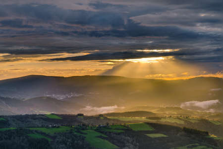 Sunbeams through the clouds at sunset in the mountains of San Roman, Cervantes, Lugo, Galiciaの写真素材