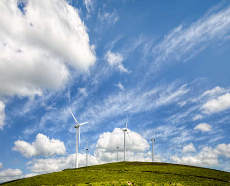 wind turbines on a hill under a blue sky with white clouds, in the Serra do Xistral, Lugo, Galicia