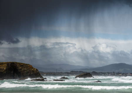 Rain showers blown by the wind between the sea and the cliffs, in Ribadeo, Galicia