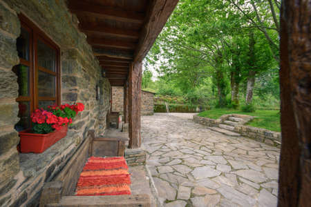 The Wooden Porch of a restored Old Manor House facing the cobblestone and the oak garden.