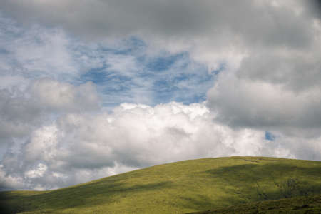 Sky alternating clouds and clearings over the green hills of the Xistral Mountain Range in northern Galiciaの写真素材