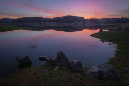 cold winter sunset over the river, with purple clouds reflected in the calm waters, in Guntin, Galiciaの写真素材