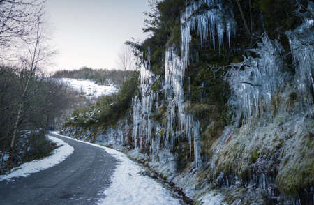 Dangerous winter conditions on a road after a freezing night leave the slopes covered in icicles in the Courel mountain rangeの写真素材