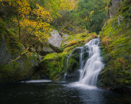 Small waterfall over a pool between granite rocks and autumn forest in the Ribeira Sacra de Ourense in Galiciaの写真素材