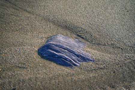 Fluorescent blue slate rock half buried in the sand of a beach in Loiba Espasante Ortigueira Galiciaの写真素材