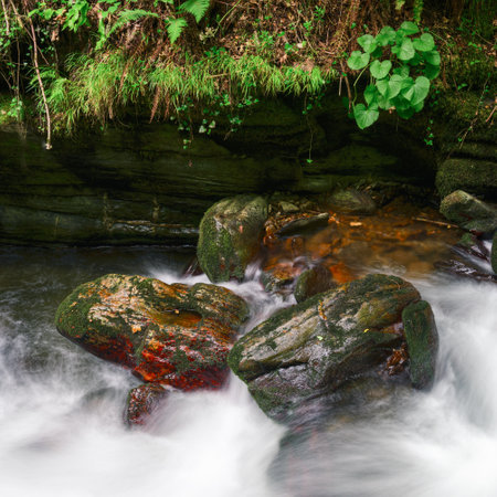 Large boulders of red quartz polished by water in a river in the Courel Mountains Geopark in Lugo...