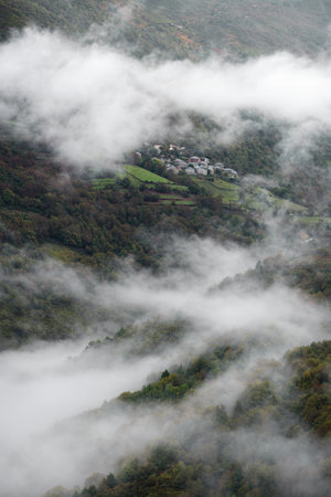 Low clouds parade between chestnut forests and small villages in Ancares Mountain Range in Cervantes...
