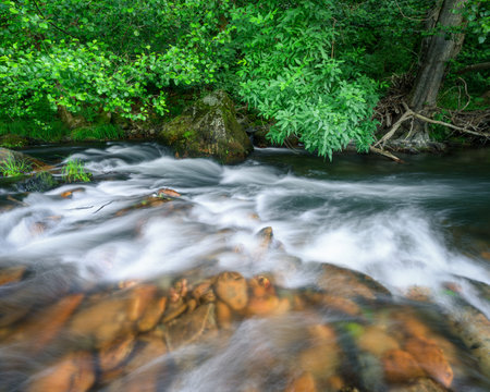 Reddish rock bowls under the crystal clear water of a mountain river in Ancares Mountain Range in Cervantes Lugo Galiciaの写真素材
