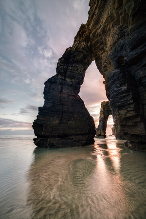 The sunrise behind the arches of As Catedrais beach creates a scene of strong contrast in Ribadeo Lugo Galiciaの写真素材