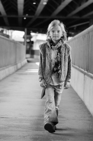 Young pretty little girl walking along the street. Monochrome full length portraitの写真素材