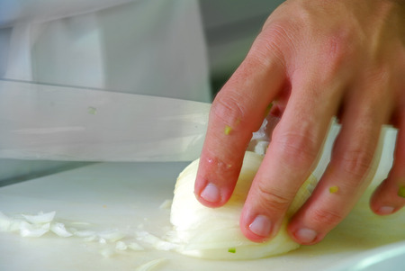 Hand with knife cutting onionの写真素材