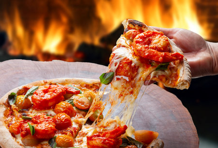 eating slice of pizza by hand, shrimp pizza with cherry tomatoesの写真素材