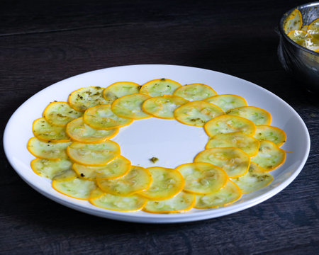 A serving of zucchini slices on a pristine white plate. This tasty dish features fresh produce cooked to perfection, ideal for a healthy mealの写真素材