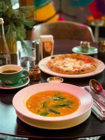 Enjoy a delectable bowl of soup and a slice of irresistible pizza at a trendy restaurant settingの写真素材