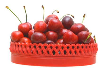 Sweet cherry fruits in a red plate on a white background.                    の写真素材