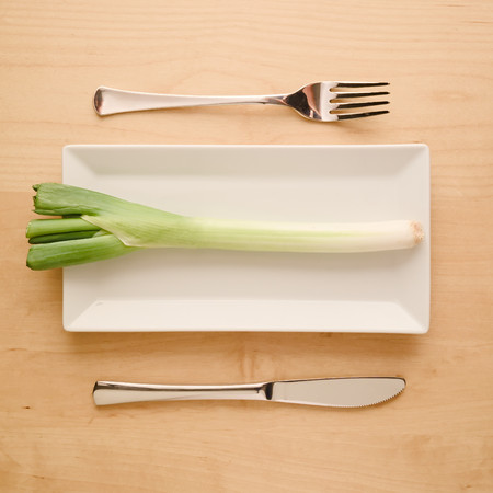 Concept of vegan and vegetarian low-carb diet. A single raw and uncut scallion or spring onion on a...