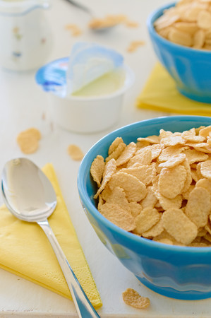 Cornflake cereals with greek yogurt in blue ceramic pot on the side with open yogurt and yellow...