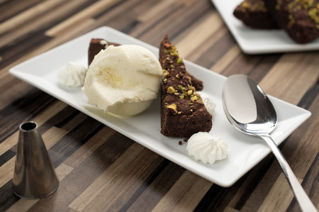Dark chocolate and pistachio ice cream cake in restaurant setting. Selective focus on front slice of cake.の写真素材