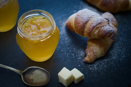 Homebaked Puff-pastry butter croissants with homemade orange marmalade and butter. Rustic setting. Selective focus.の写真素材