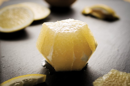 Peeled organic grapefruit with zest on dark background. Selective focus on middle top of grapefruit. Dramatic backlight and dark shadows.の写真素材