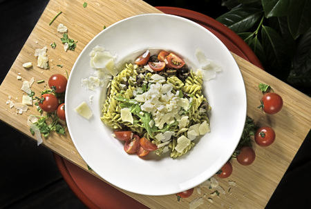 Fusilli pasta with parmesan cheese, rucola, olives and cherry tomatoesの写真素材