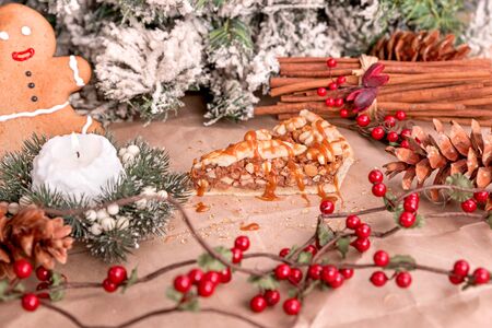 Homemade walnut pie with caramel decorated with cinnamon, candles, pines served on recycled paper.の写真素材