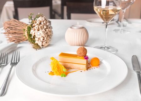 Delis foie gras and mango - praline of foie gras and poker dust, gel mango, sphere and sponge, served in a white plate.の写真素材