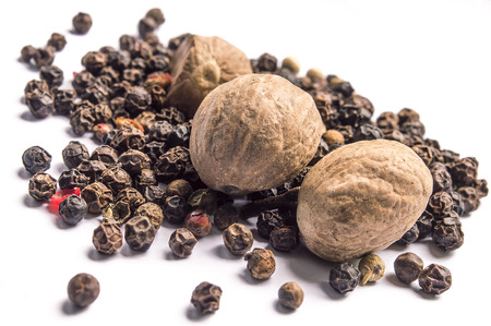 Nutmegs and black pepper on white backgroundの写真素材