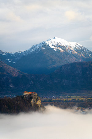 Castle Bled looking over Lake Bled, covered in fog, with the Julian Alps in the backgroundの写真素材
