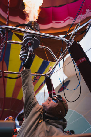 A pilot firing up the burner and being illuminated by the flames. Taken at 42nd International Balloon Festival at Chateau D'Oex in January 2023.のeditorial素材