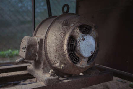 Old electric motor powering a table saw (bench saw). Vintage industrial equipment concept. Rusty and dirty electric engine power rotating machineの写真素材