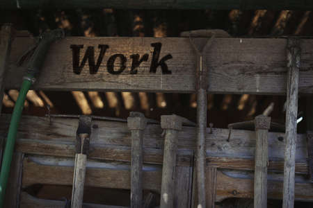 Old wooden vintage workshop with working tools and the text Work. Gardening tools hanging on a wooden grunge shed, garden maintenance conceptの写真素材