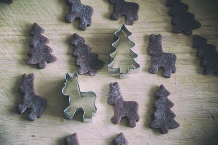Close up of raw dough for gingerbread cookie on the kitchen table. Baking homemade Christmas cookies. Cutting out a ginger bread x-mas symbols with cutters, Top view. Preparing to celebrate Christmasの写真素材