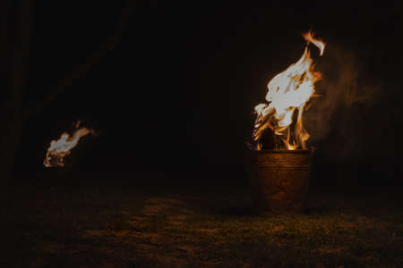Burning firewood in iron pail for heating. Wood burns in a metal buckets to protect trees from freezing. Saving an orchard from frostの写真素材