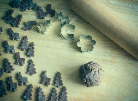 Close up of raw dough for gingerbread cookie on the kitchen table. Baking homemade Christmas cookies. Cutting out a ginger bread x-mas symbols with cutters, Top view. Preparing to celebrate Christmasの写真素材
