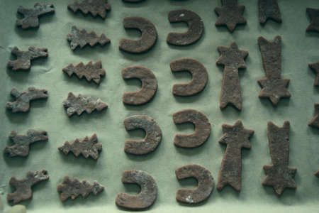 Close up of raw dough for gingerbread cookie on the kitchen table. Baking homemade Christmas cookies. Cutting out a ginger bread x-mas symbols with cutters, Top view. Preparing to celebrate Christmasの写真素材