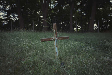 Single old grave on a traditional European cemetery in Slovakia. Aged cross tomb in the grass at grave yardの写真素材