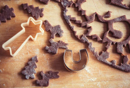 Close up of raw dough for gingerbread cookie on the kitchen table. Baking homemade Christmas cookies. Cutting out a ginger bread x-mas symbols with cutters, Top view. Preparing to celebrate Christmasの写真素材