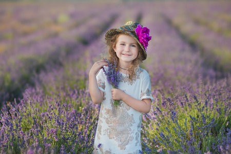 Young beautiful girl walking on the lavender field on a weekend day in wonderful dresses and hatsの写真素材