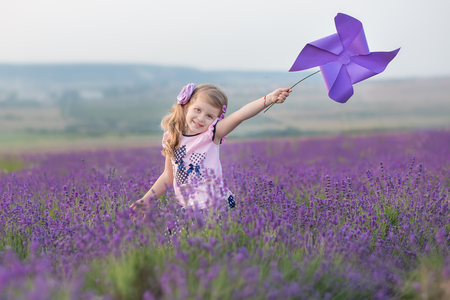 Young mother with young daughter smiling on the field of lavender .Daughter sitting on mother hands.Girl in colorful dress and mother in dark blue dressの写真素材