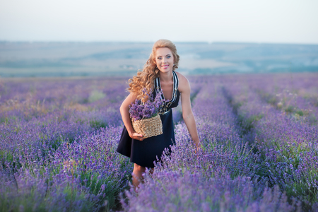 Young mother with young daughter smiling on the field of lavender .Daughter sitting on mother hands.Girl in colorful dress and mother in dark blue dressの写真素材