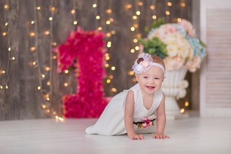 Cute baby girl 1-2 year old sitting on floor with pink balloons in room over white. Isolated....