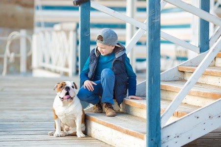 Nice looking handsome boy on beach with english bulldogの写真素材