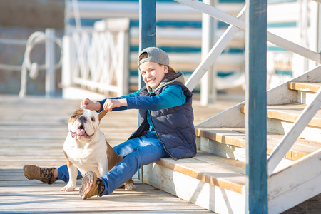Nice looking handsome boy on beach with english bulldogの写真素材