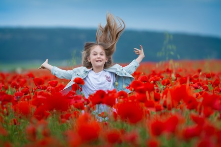 Beauty blue eyes teen enjoy summer days .Cute fancy dressed girl in poppy field. Field of blooming poppiesの写真素材