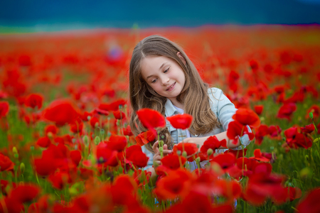 Beauty blue eyes teen enjoy summer days .Cute fancy dressed girl in poppy field. Field of blooming poppiesの写真素材