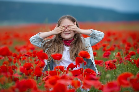 Beauty blue eyes teen enjoy summer days .Cute fancy dressed girl in poppy field. Field of blooming poppiesの写真素材